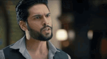 a man with a beard is making a funny face while standing in a room .