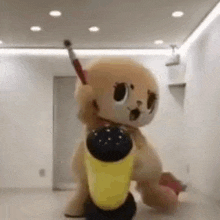 a stuffed animal in a mascot costume is standing in a room holding a yellow object .