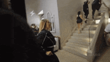 a woman walking down a set of stairs with the word zeus on the bottom left