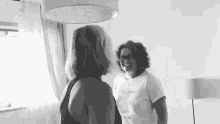 two women are standing next to each other in a room and talking to each other .
