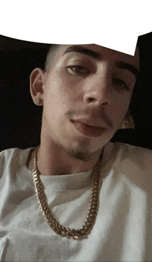 a man wearing a gold chain around his neck looks at the camera