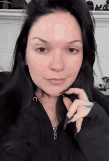 a woman without makeup is wearing a black hoodie