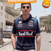 a man wearing a red bull shirt is standing on a street
