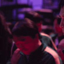 a group of people are standing in a dark room with purple lighting
