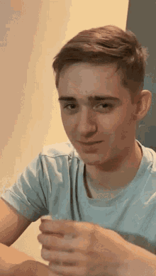 a young man wearing a light blue shirt is sitting at a table