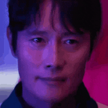 a close up of a man 's face with purple and blue lights behind him .