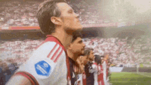 a group of soccer players are standing in a line on a soccer field with their eyes closed .