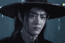 a man with long hair wearing a black hat