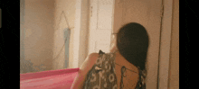 a woman in a dress is standing in front of a door and looking out .