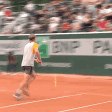 a man playing tennis on a court with a bnp pa sign in the background