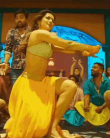 a woman in a crop top and yellow skirt is dancing in front of a crowd