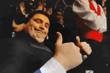 a man in a suit is giving a thumbs up sign