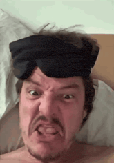 a man with a sleep mask on his head making a funny face .