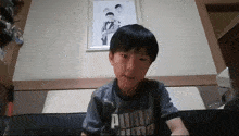 a young boy wearing a puma shirt sits on a couch