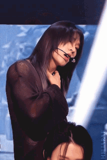a woman wearing a microphone stands in front of a screen that says heliababy on it