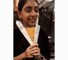 a young girl is holding a piece of paper in her hand and smiling .