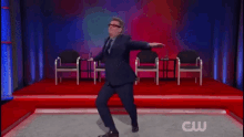 a man in a suit and tie is dancing on a stage with a cw logo in the corner