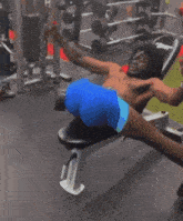 a shirtless man in blue shorts is laying on a bench with his legs crossed