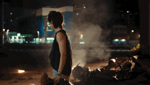a woman in a black tank top is standing in front of a building with the letter e on it