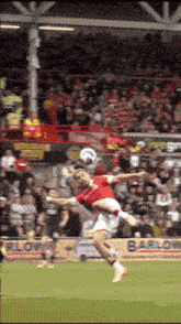 a soccer player in a red shirt jumps in the air to head the ball
