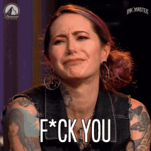 a woman with a tattoo on her arm says f * ck you on a screen