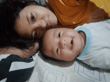 a woman and a baby are laying on a bed