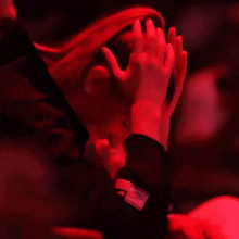 a person covering their face with their hands with a red background