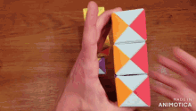 a person is holding a colorful cube that is made in animotica
