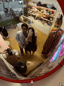 a man and a woman are taking a picture in front of a mirror with the letter a on the bottom