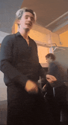 a man in a black shirt is dancing in a room with other people