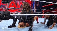 a woman is wrestling another woman in a wrestling ring while a referee watches .
