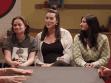 a group of women are sitting around a table playing a game of cards