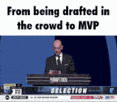 a man in a suit and tie is giving a speech at a podium that says draft 2025 selection