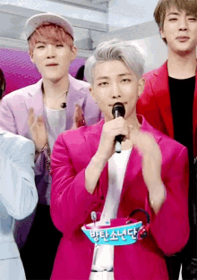 a man in a pink jacket is holding a microphone in his mouth .