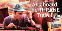 a man is playing with a train set with the words all aboard the thrane train behind him