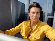 a man in a yellow shirt is looking out a window