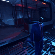 a man in a blue suit and tie is walking in a dark room