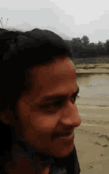 a man 's face is shown in a blurry photo with a river in the background