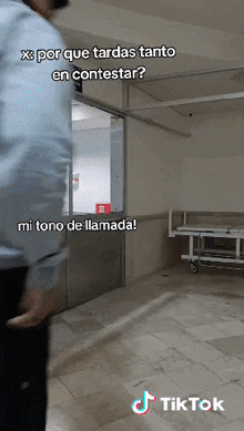 a man in a blue shirt is standing in a hospital room with a sign that says x por que tardas tanto en contestar