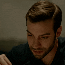 a close up of a man 's face with a beard wearing a black shirt