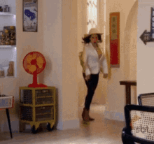 a woman is standing in a hallway with a fan and a sign that says 66