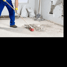 a man is cleaning a concrete surface with a broom and hose