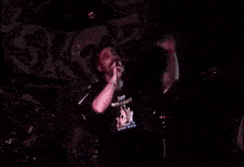 a man singing into a microphone wearing a black shirt that says stop our brutality