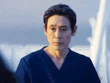 a man in a blue scrub top looks to the side