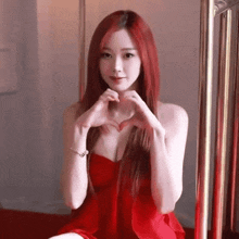 a woman in a red dress makes a heart shape with her hands