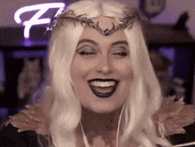 a woman in a white wig and crown is smiling .