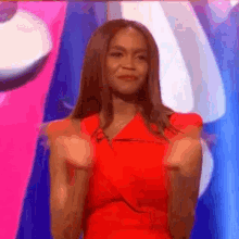 a woman in a red dress is giving a fist pump