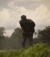 a man is standing in a field of tall grass