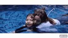 two girls are swimming in a pool together and one of them is hugging the other .
