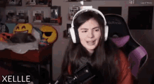 a woman wearing headphones is sitting in a chair in front of a microphone in a room .